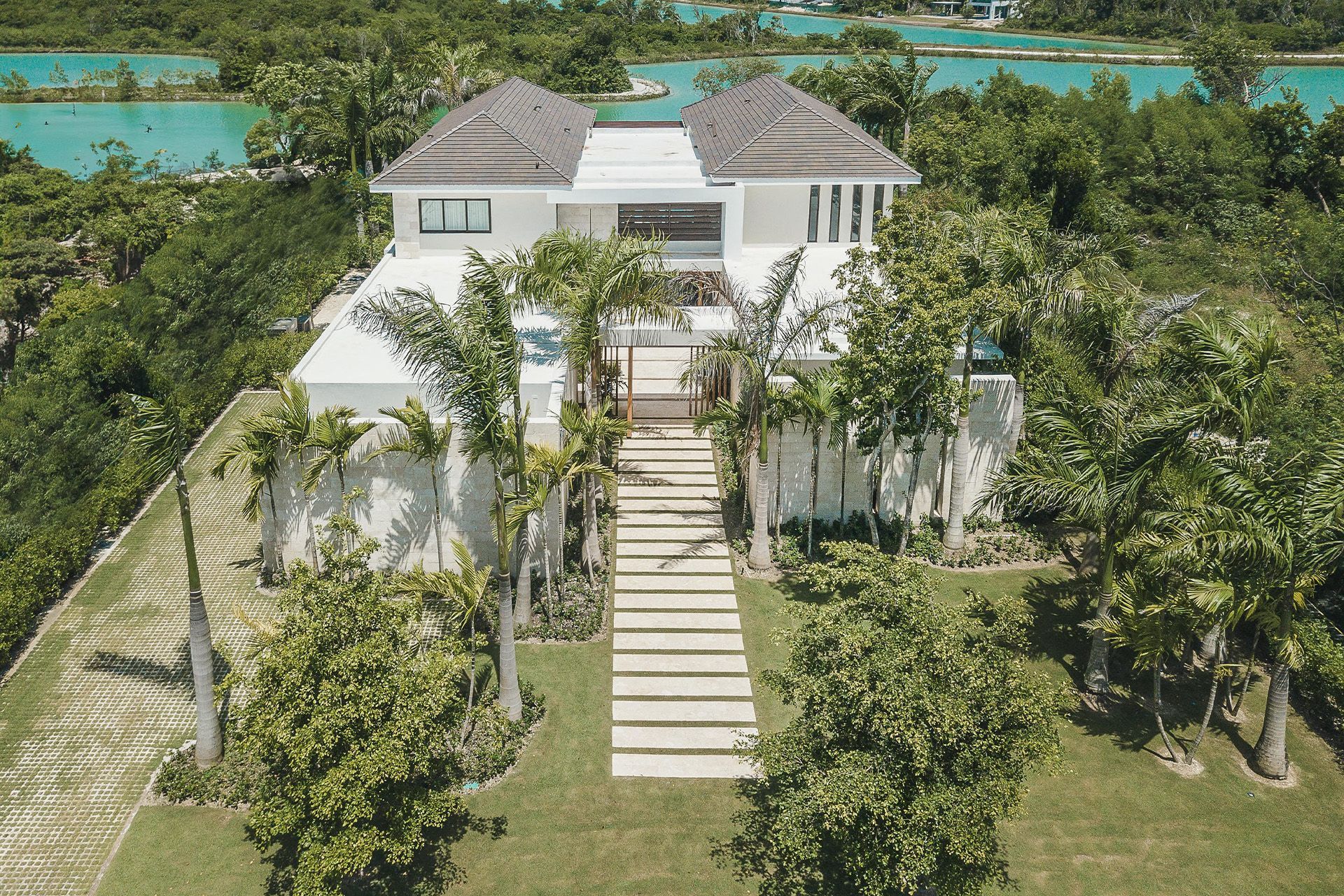 White tropical villa with stairs, surrounded by palm trees and overlooking turquoise water. Mangle 15
