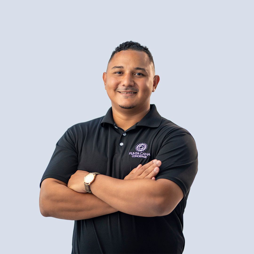 Smiling person in a black polo shirt with arms crossed against a light blue background