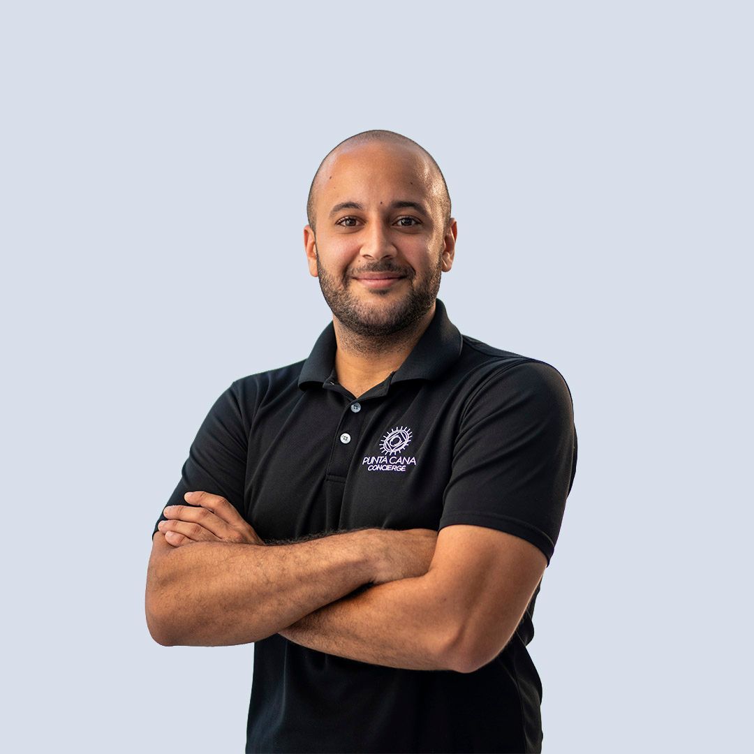 Man with folded arms in a black polo shirt against a light blue background
