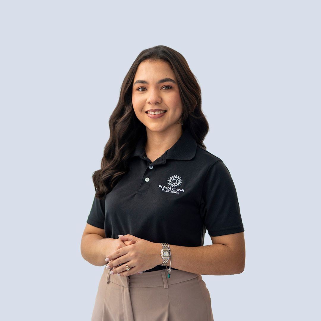 Woman standing and smiling in a black polo and tan pants against a light gray background