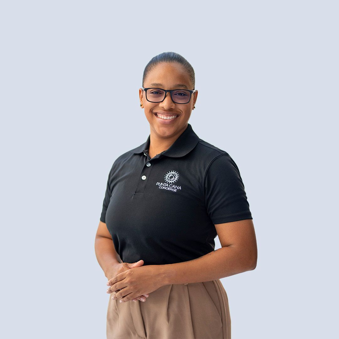 Smiling person in a black polo and tan skirt against a light gray background