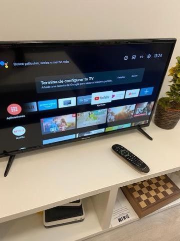 Un televisor sobre un soporte blanco muestra la pantalla de inicio de una transmisión en directo