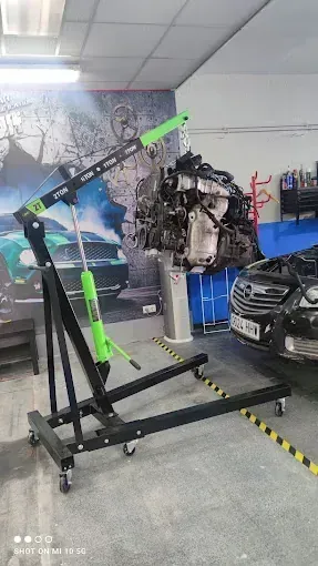 Un motor de coche está encima de una grúa en un garaje.