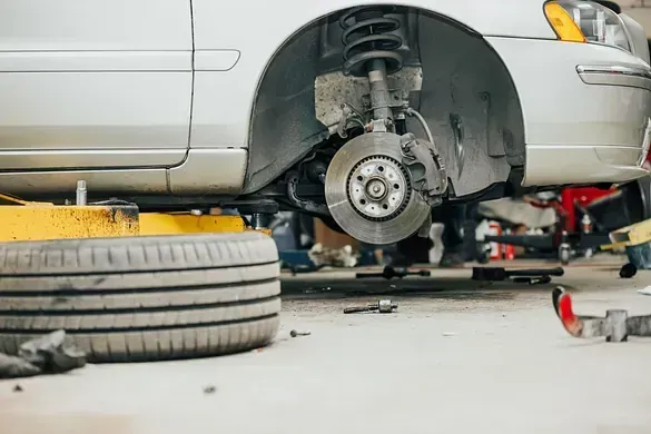Un coche está siendo reparado en un garaje con un neumático en el suelo.