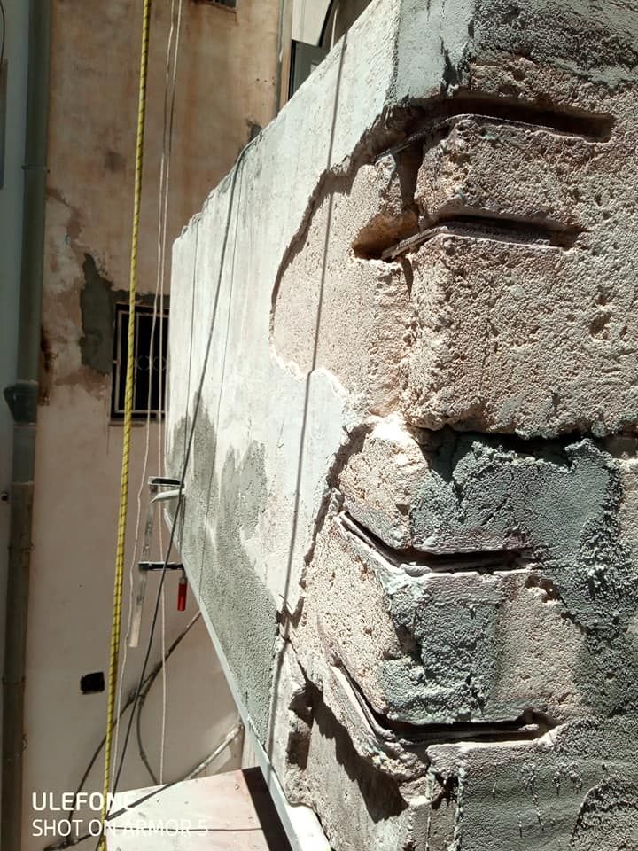 Un primer plano de una pared de ladrillos con una cinta métrica colgando de ella.