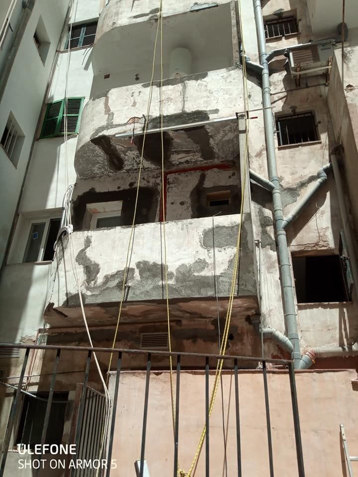 Un edificio en construcción con un balcón y una cuerda colgando de él.