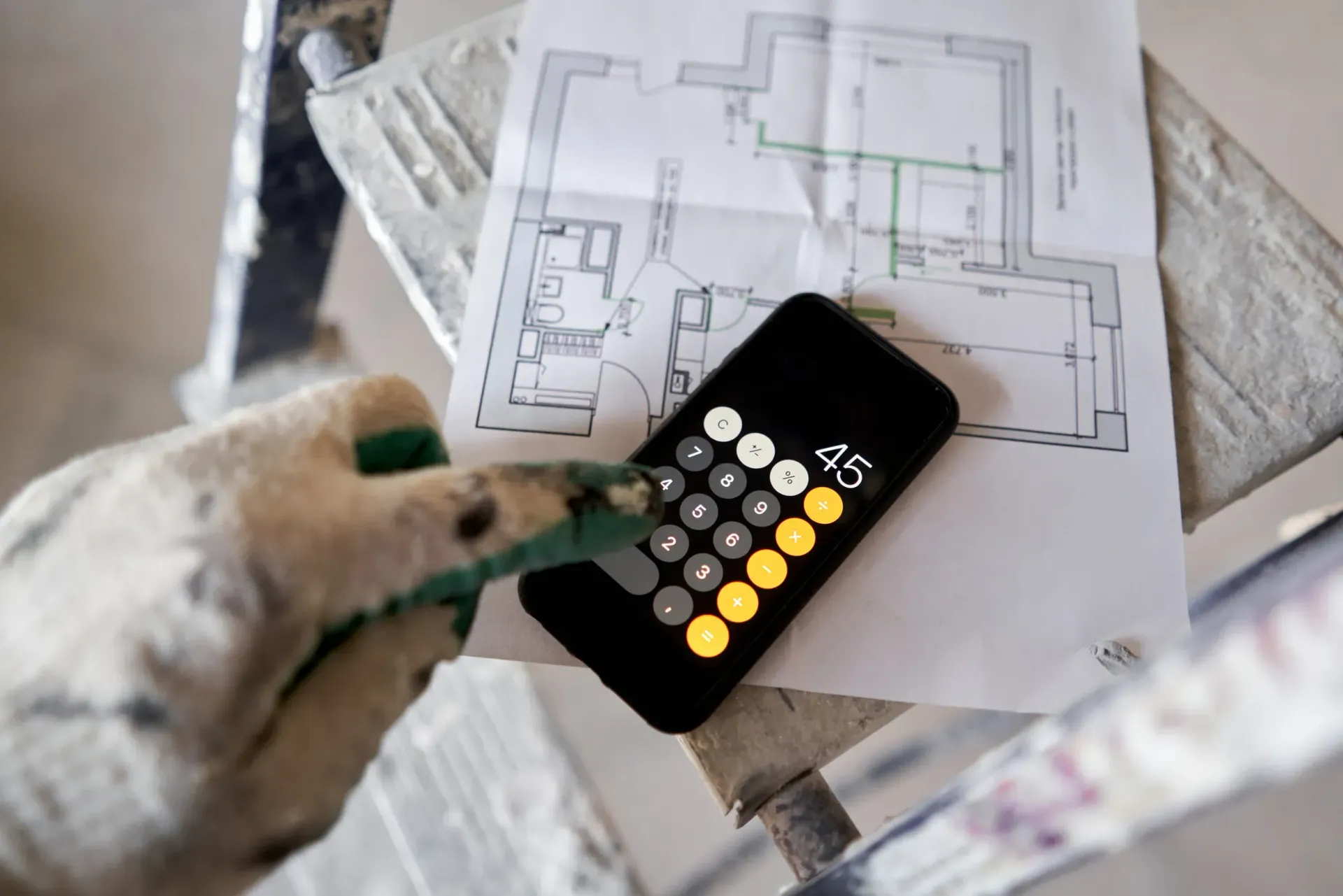 Una persona está usando una calculadora al lado de un plano del piso.