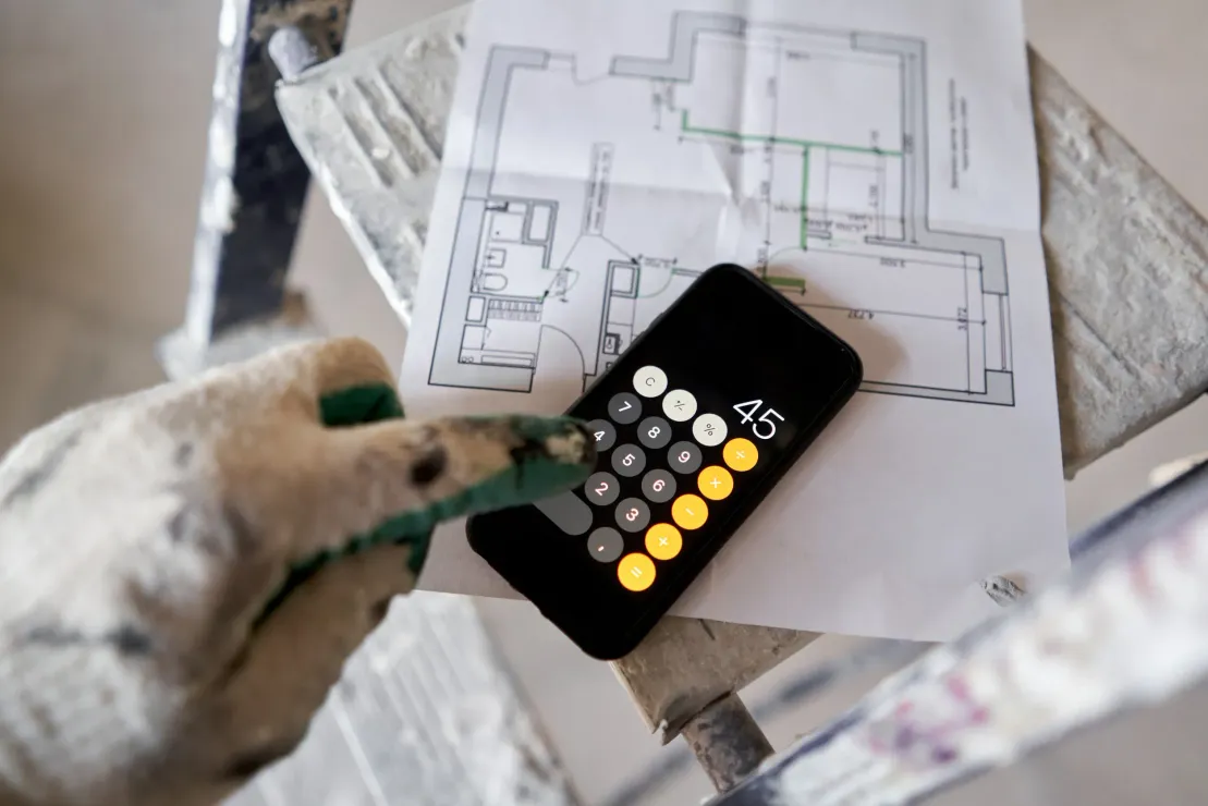 Una persona está usando una calculadora al lado de un plano del piso.