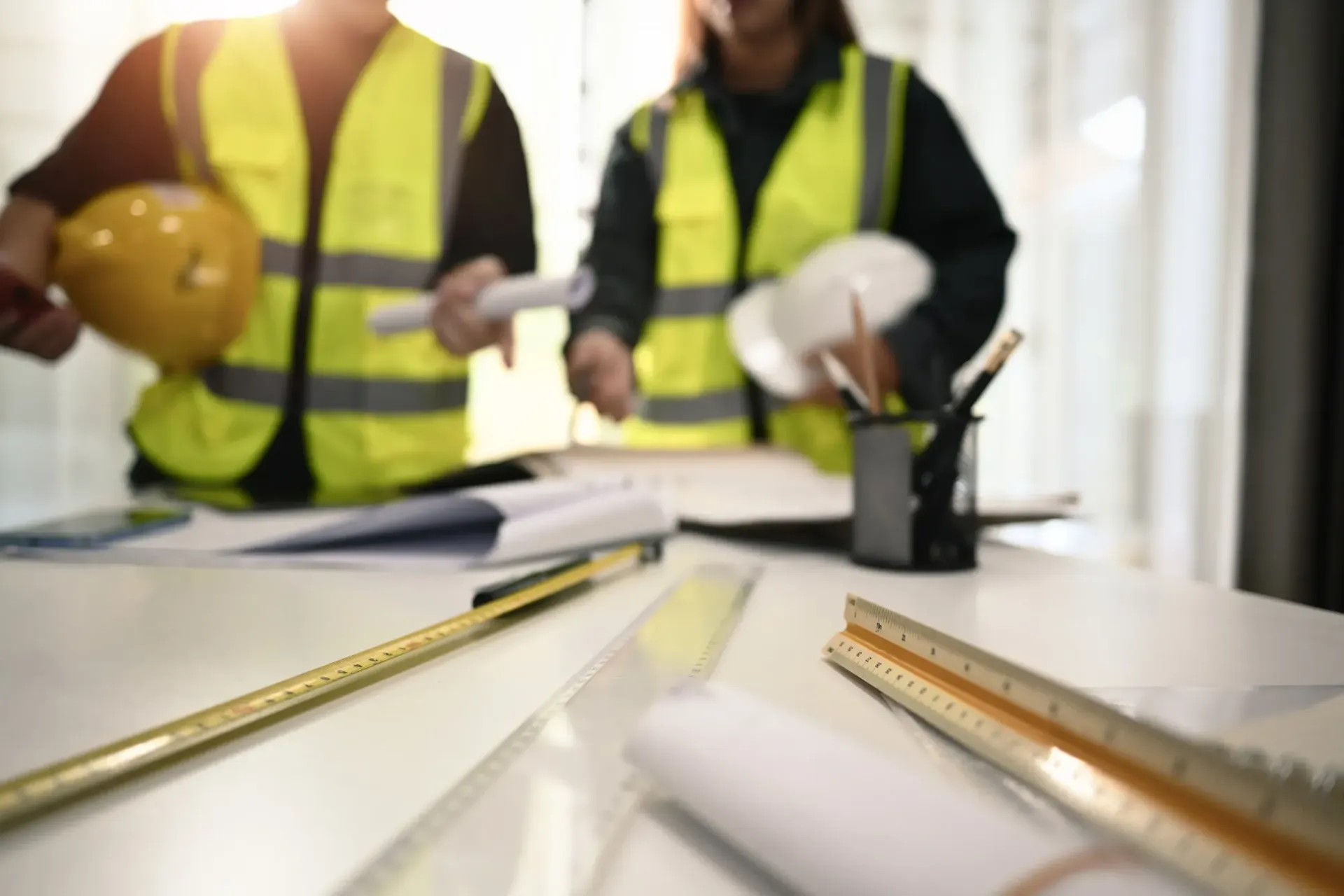 Una pareja de trabajadores de la construcción están sentados en una mesa mirando un plano.