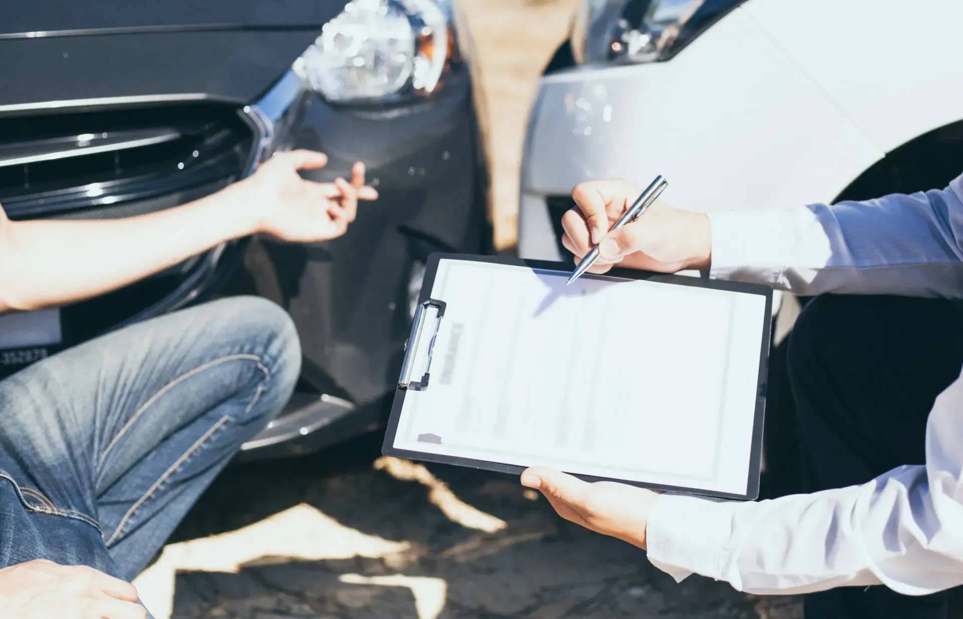 Un grupo de personas mira un portapapeles delante de un coche.