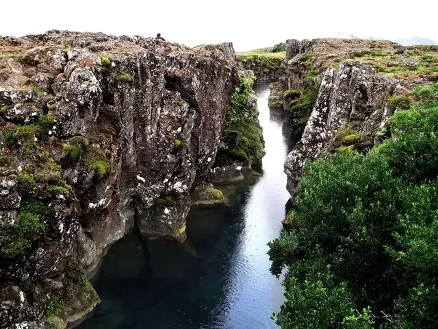 Un profundo abismo lleno de agua, bordeado por escarpados acantilados rocosos cubiertos de musgo.