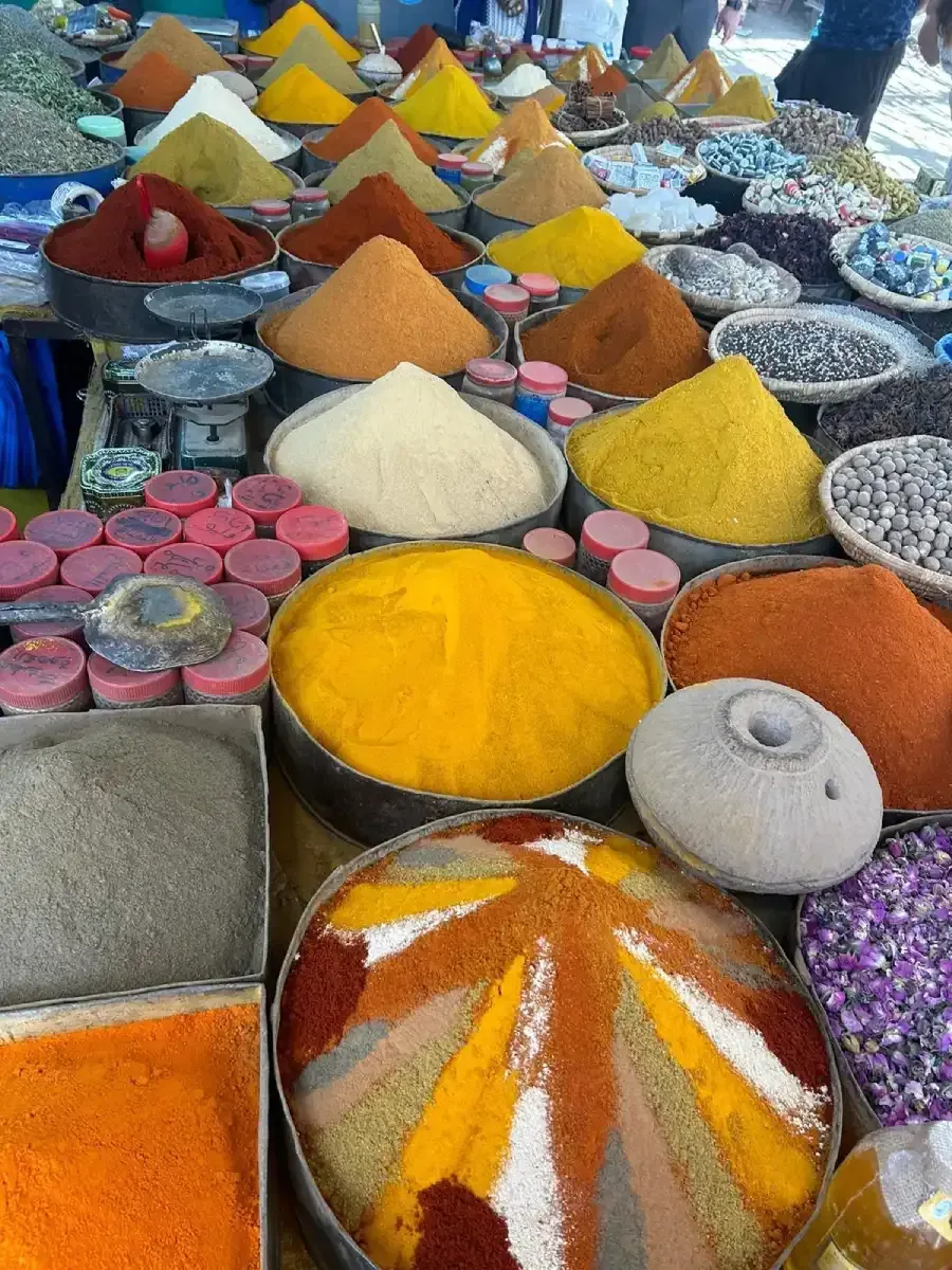 Escena callejera en Reykjavik, Islandia, con tiendas, gente, árboles y un monumento alto.