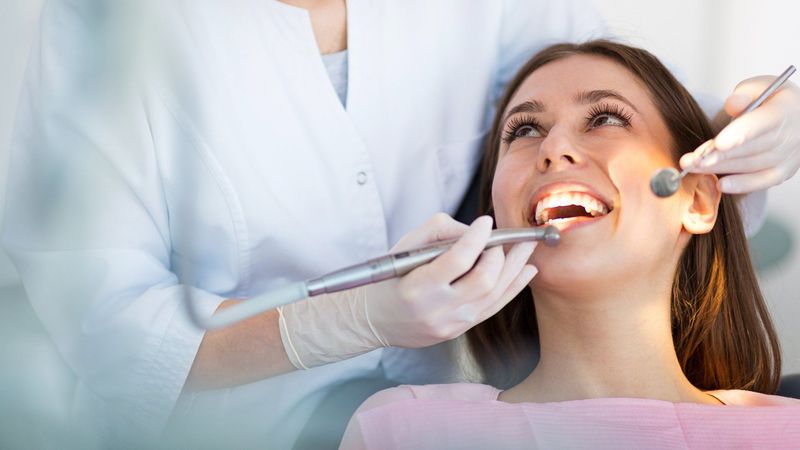 Una mujer está siendo examinada por un dentista.