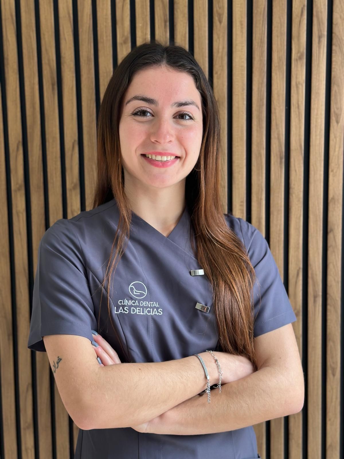Una mujer se encuentra frente a un cartel que dice Clínica Dental Las Delicias.