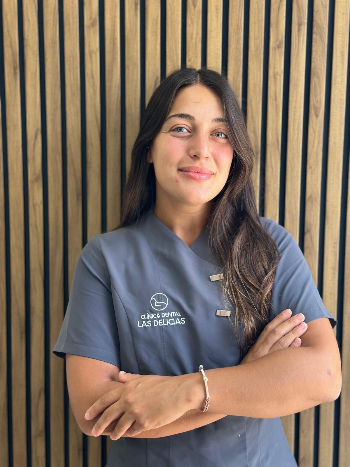 Una mujer en un consultorio dental está parada frente a una pared rayada.