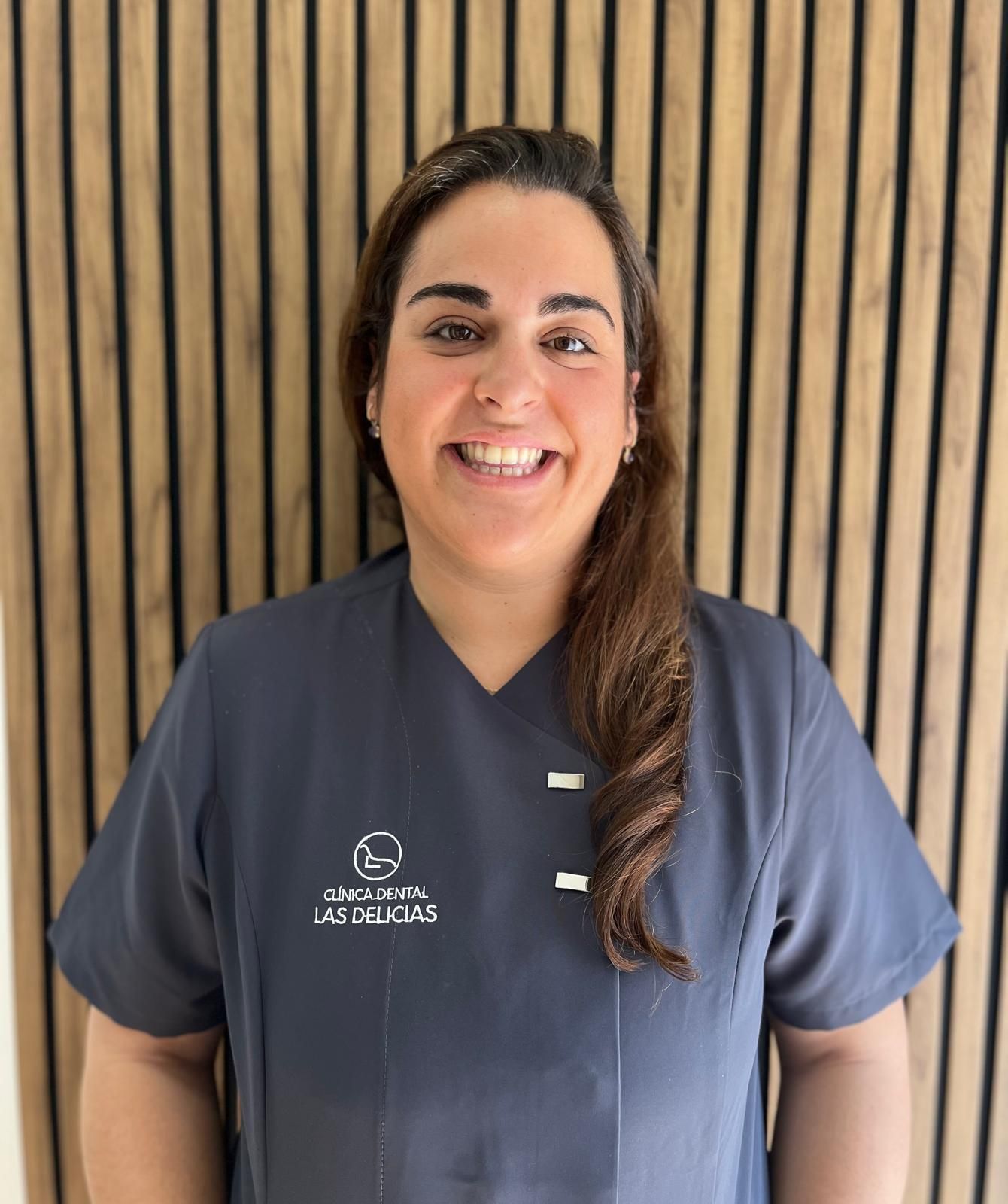 Una mujer se encuentra frente a un cartel que dice Clínica Dental Las Delicias.