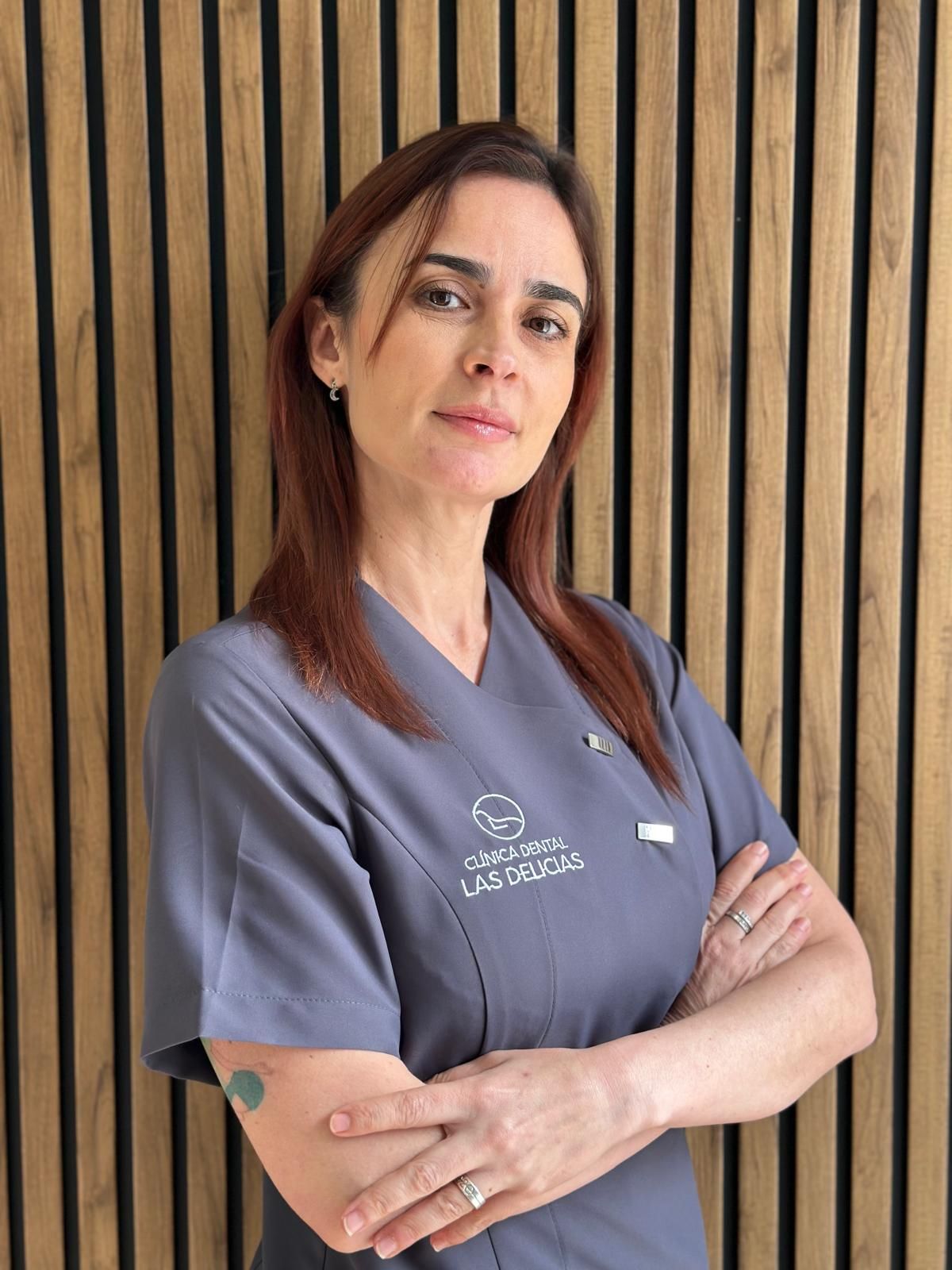 Una mujer en un consultorio dental está parada frente a una pared rayada.
