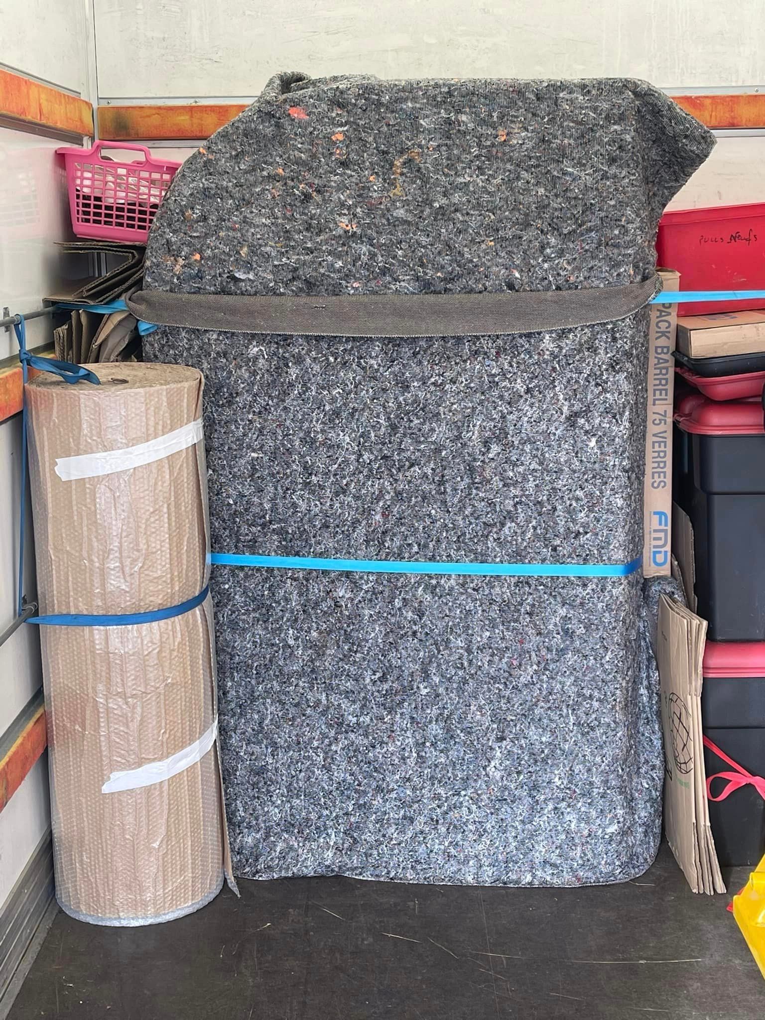 Meubles protégés par une couverture de protection grise et carton enroulé