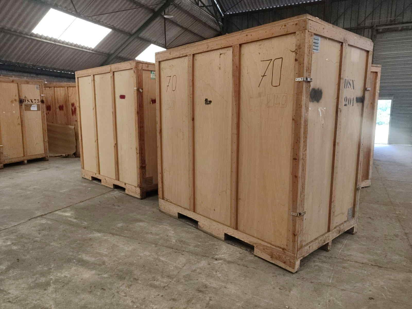 Caisses en bois étiquetées avec des numéros à l'intérieur d'un entrepôt.