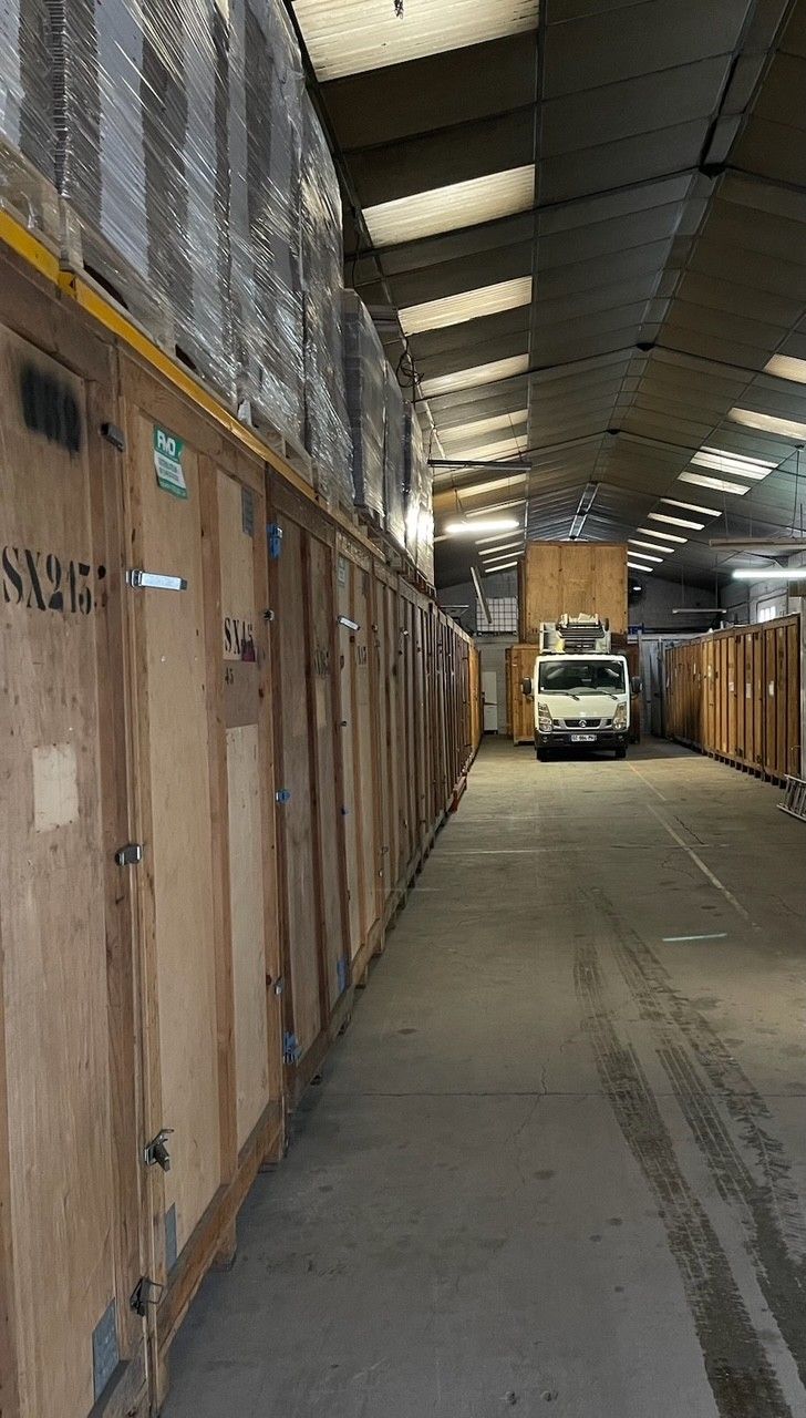 Plusieurs grandes caisses en bois alignées sur un sol en béton, probablement dans un entrepôt.