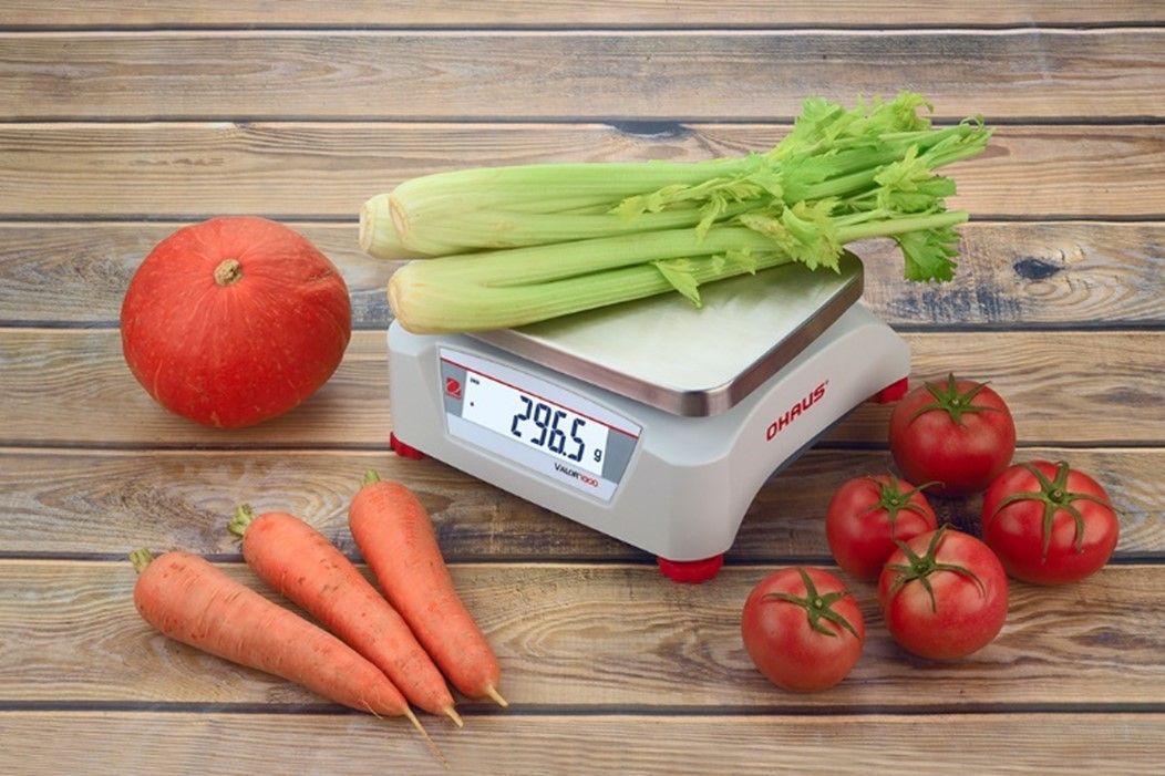 Des légumes et une balance sur une table en bois