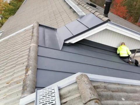 Ammattitaitoinen peltiseppä toteuttamassa kiinteistön pellityksiä