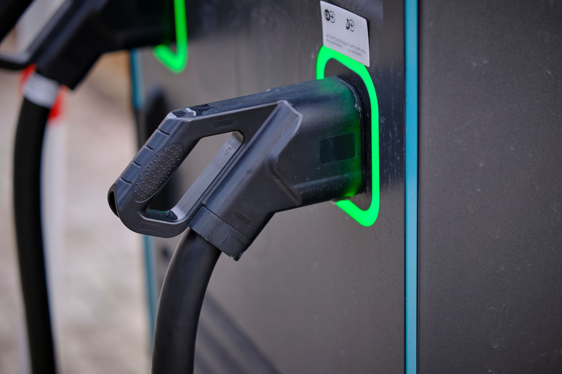 Une prise de recharge pour véhicule électrique est branchée dans une station de recharge illuminée par un anneau lumineux.