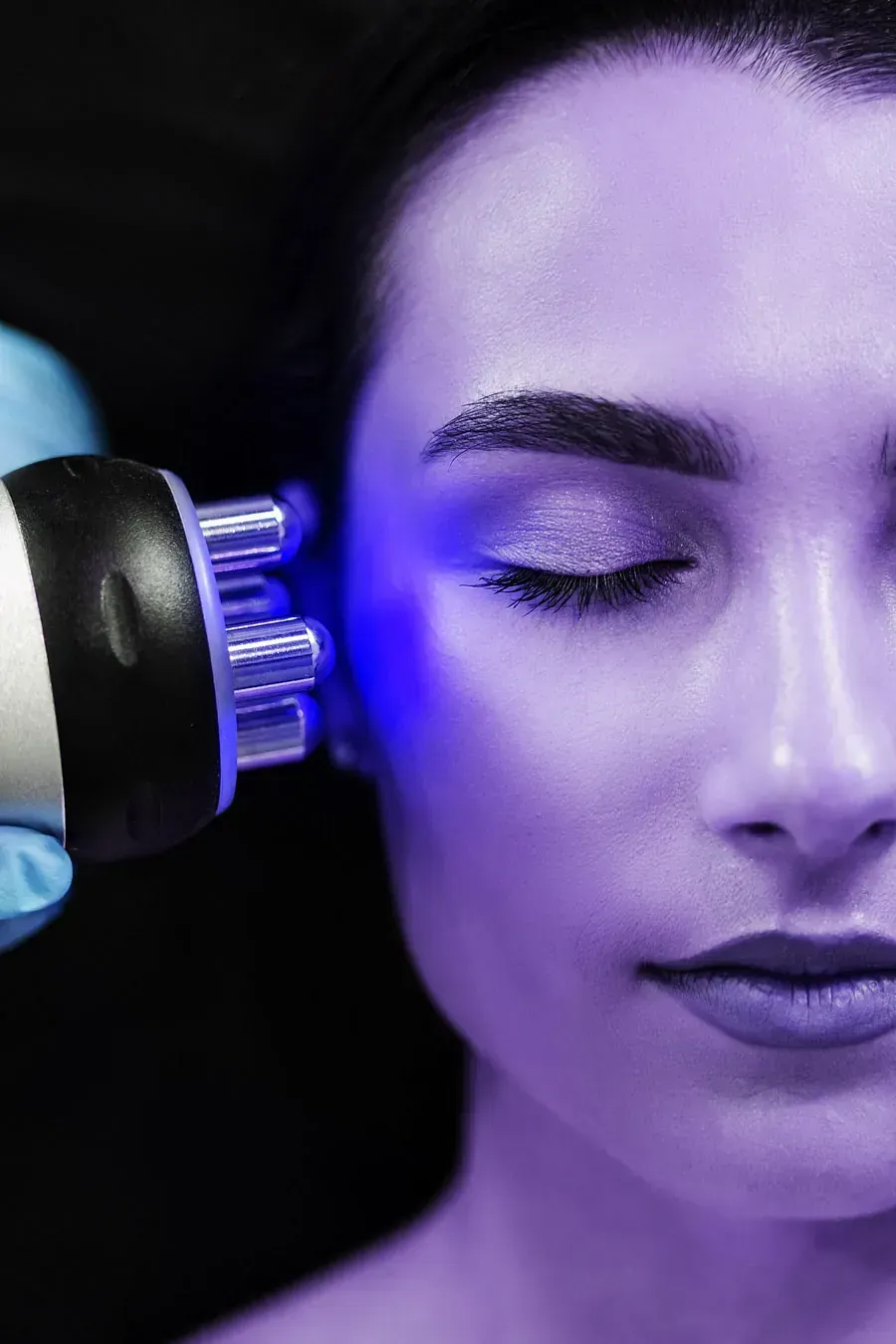 Una mujer está recibiendo un tratamiento de luz violeta en su cara.