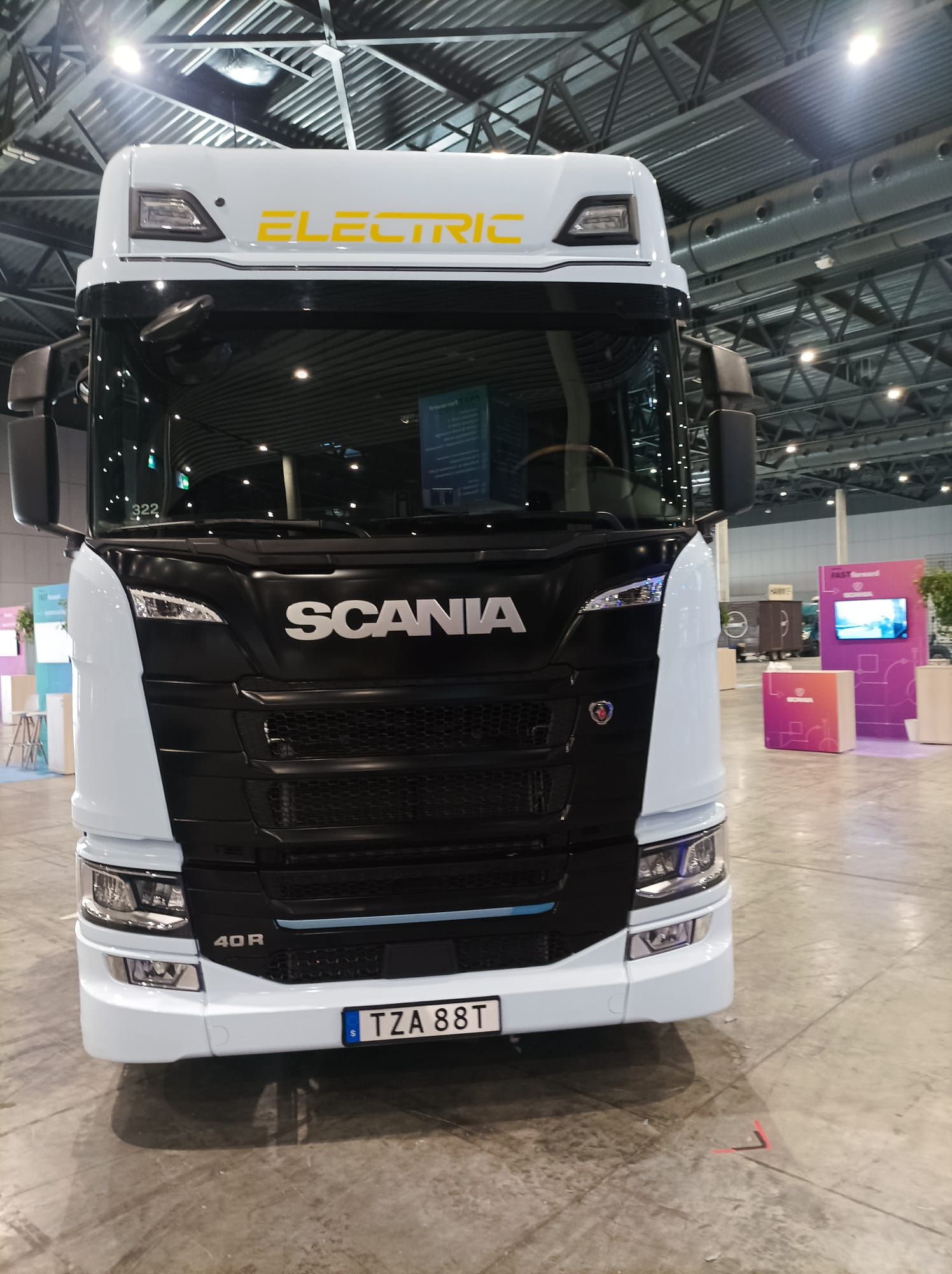 Un camión eléctrico Scania blanco y negro está estacionado en un edificio.