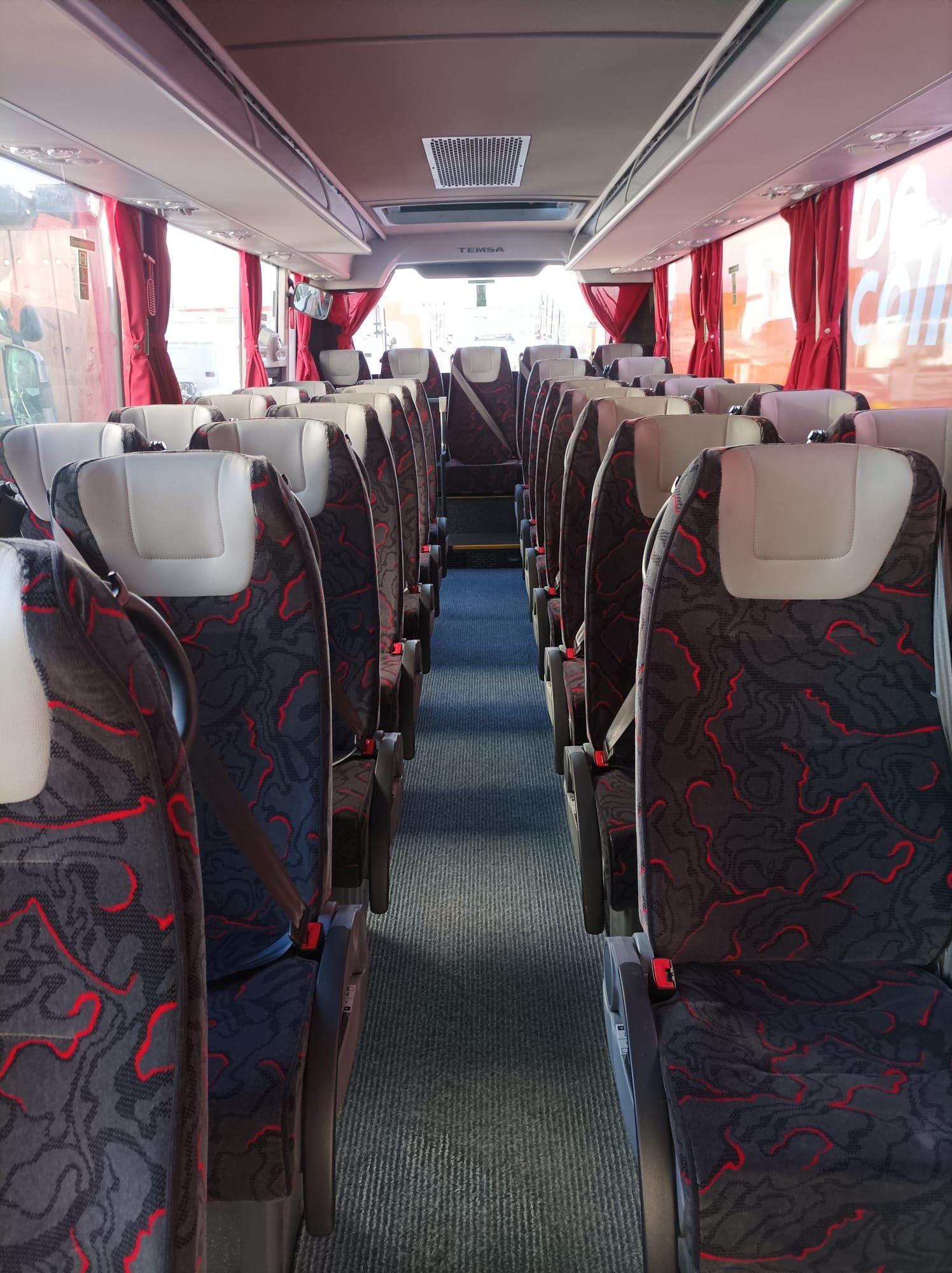 El interior de un autobús con asientos rojos y negros.