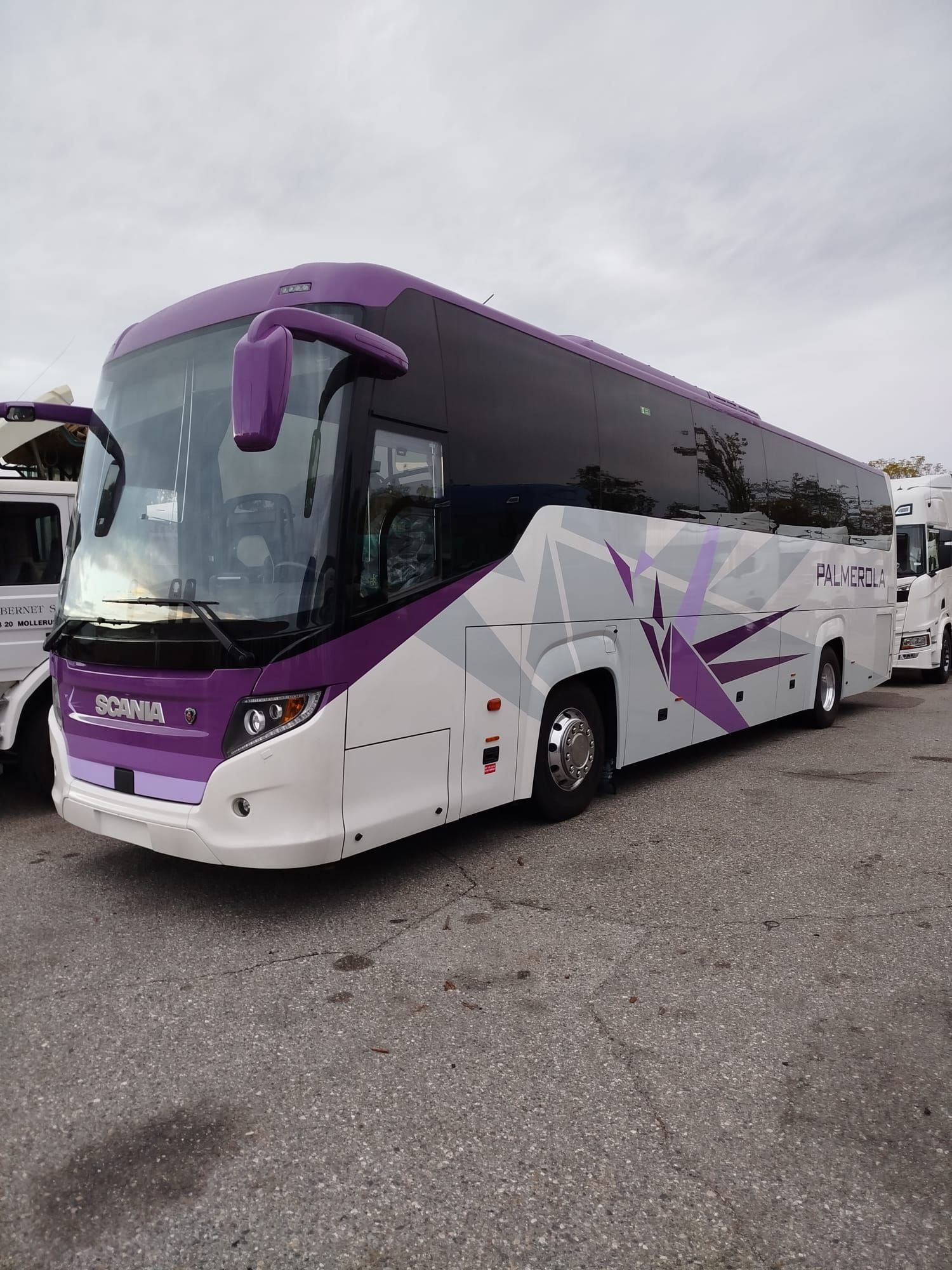 Un autobús morado y blanco está estacionado en un estacionamiento.