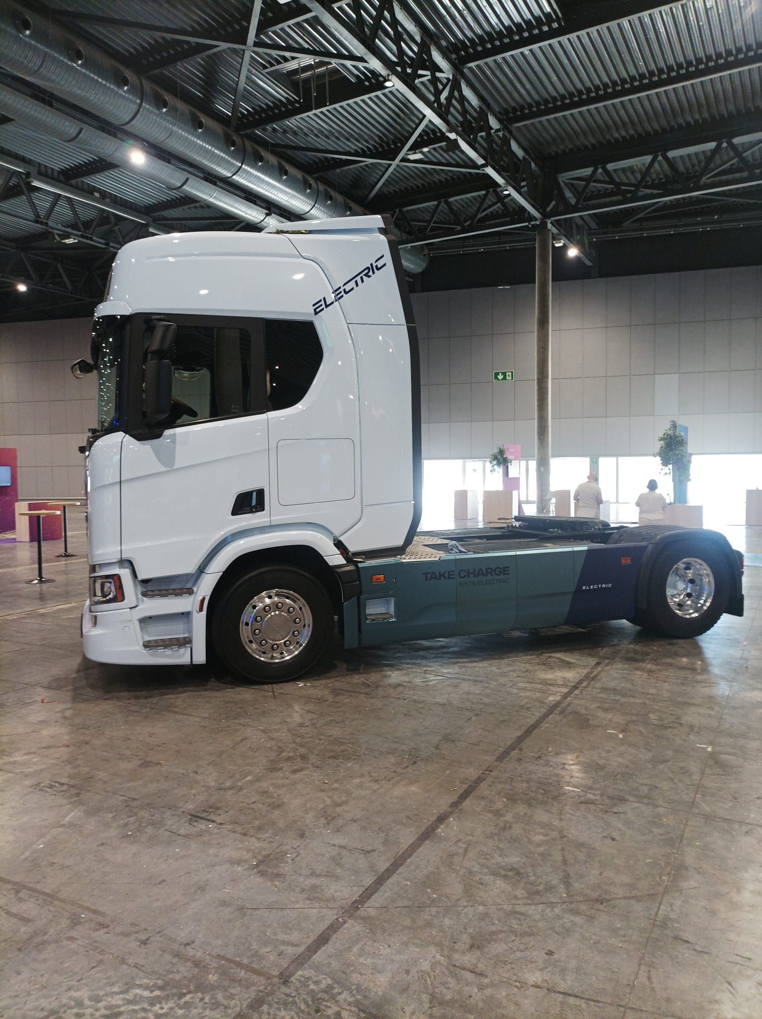 Un camión semirremolque blanco está estacionado en un gran almacén.