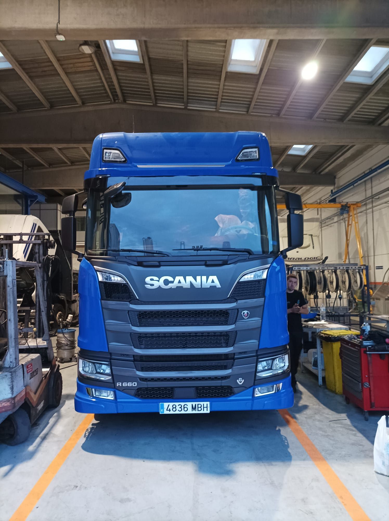 Un camión Scania azul está estacionado en un garaje.