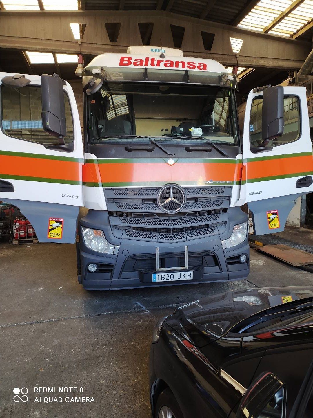 Un camión Mercedes está estacionado en un garaje con las puertas abiertas.