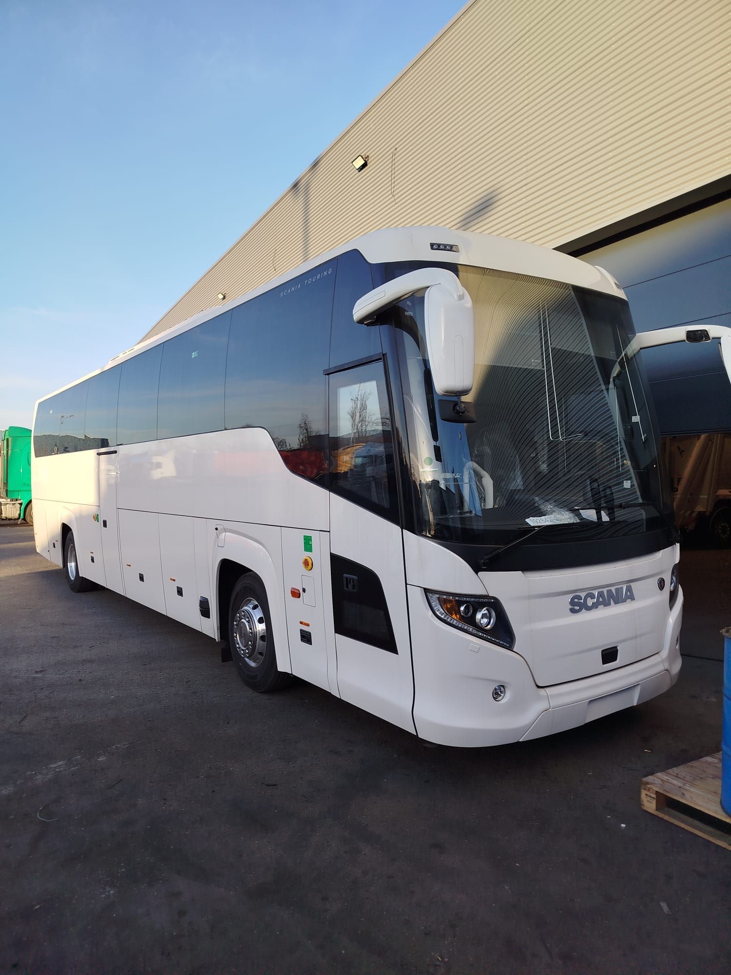 Un autobús blanco está estacionado frente a un edificio.