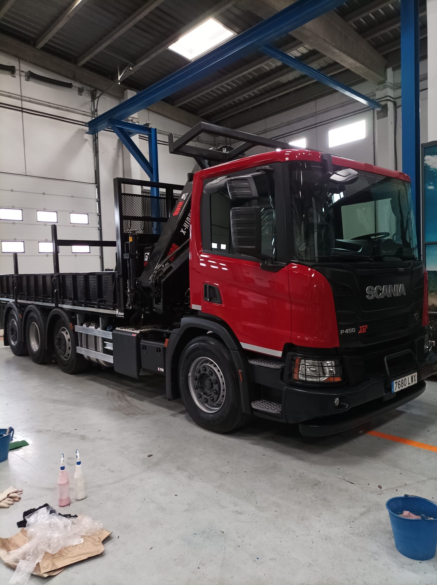 Un camión rojo con una grúa en la parte trasera está estacionado en un garaje.