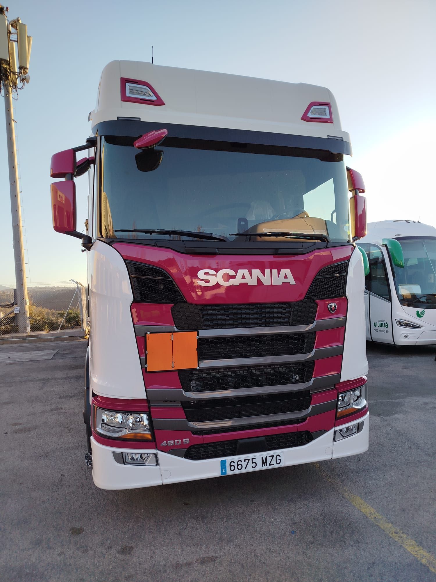Un camión Scania rojo y blanco está estacionado en un estacionamiento.