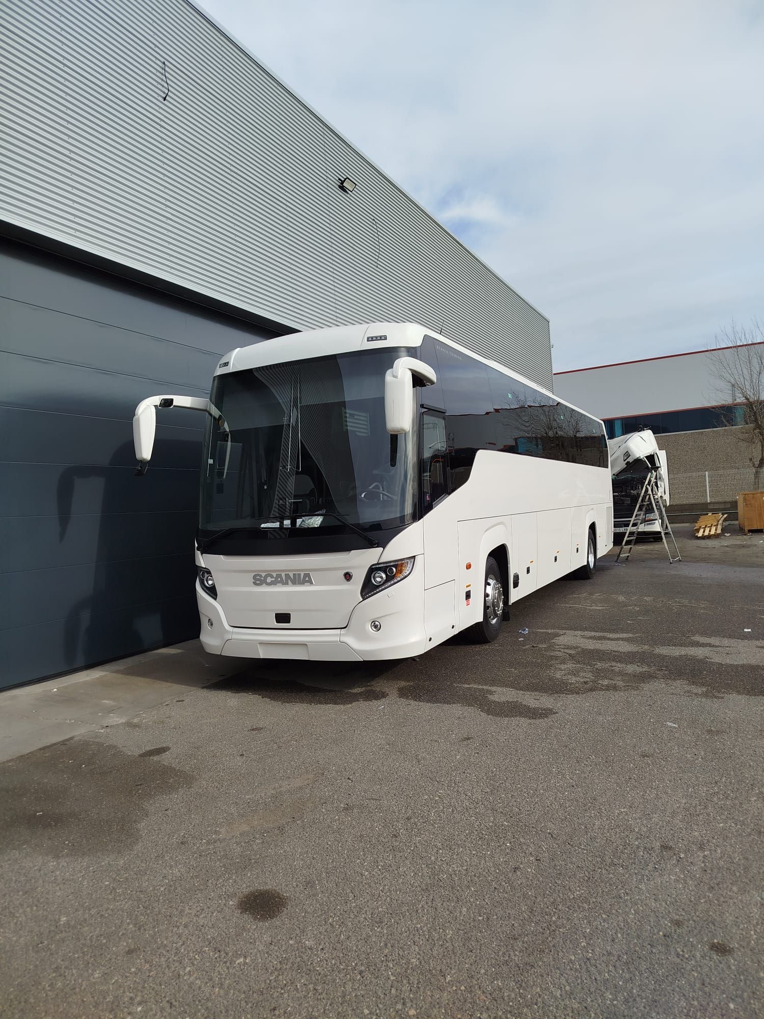 Un autobús blanco está estacionado frente a un edificio.
