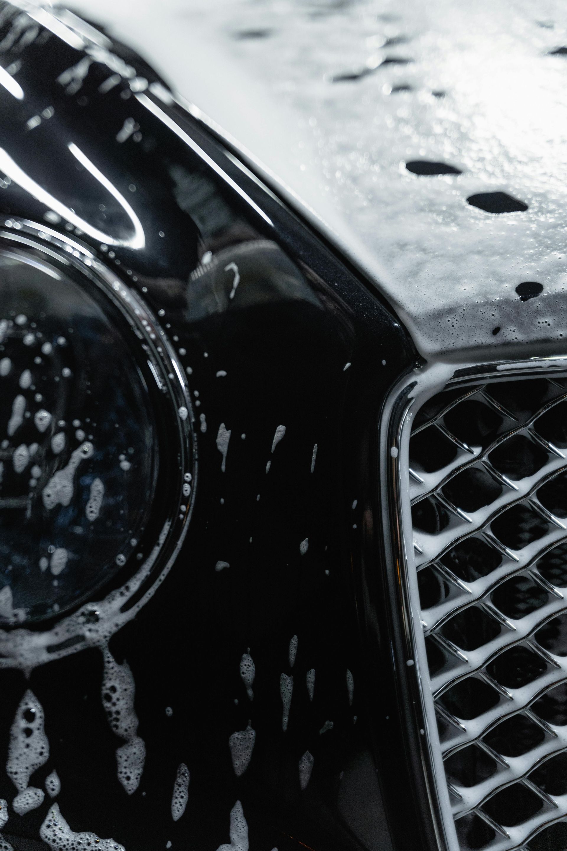 Un coche negro se está lavando con agua y jabón.