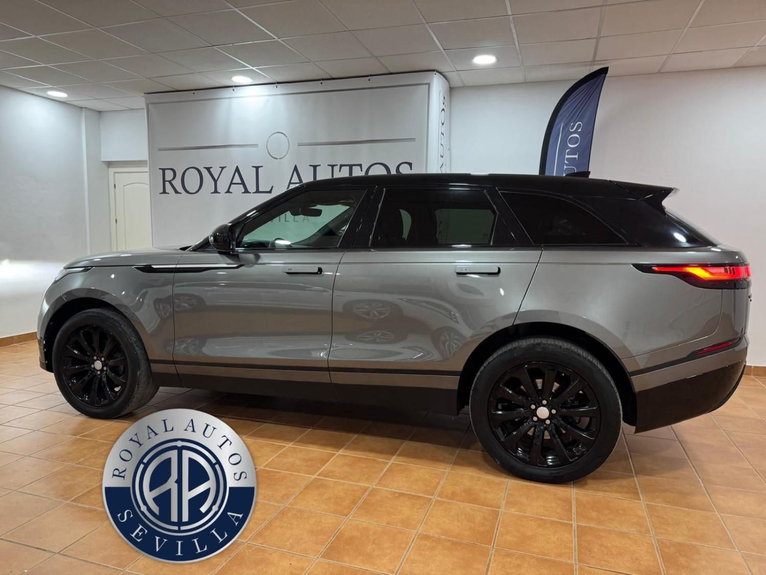 Land Rover Velar gris con ruedas negras estacionado en una sala de exposición con letrero