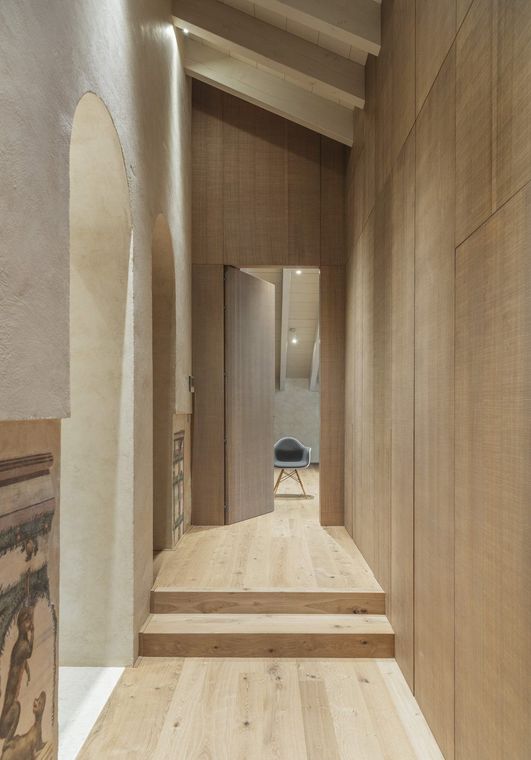 Un lungo corridoio con pavimenti in legno e una porta
