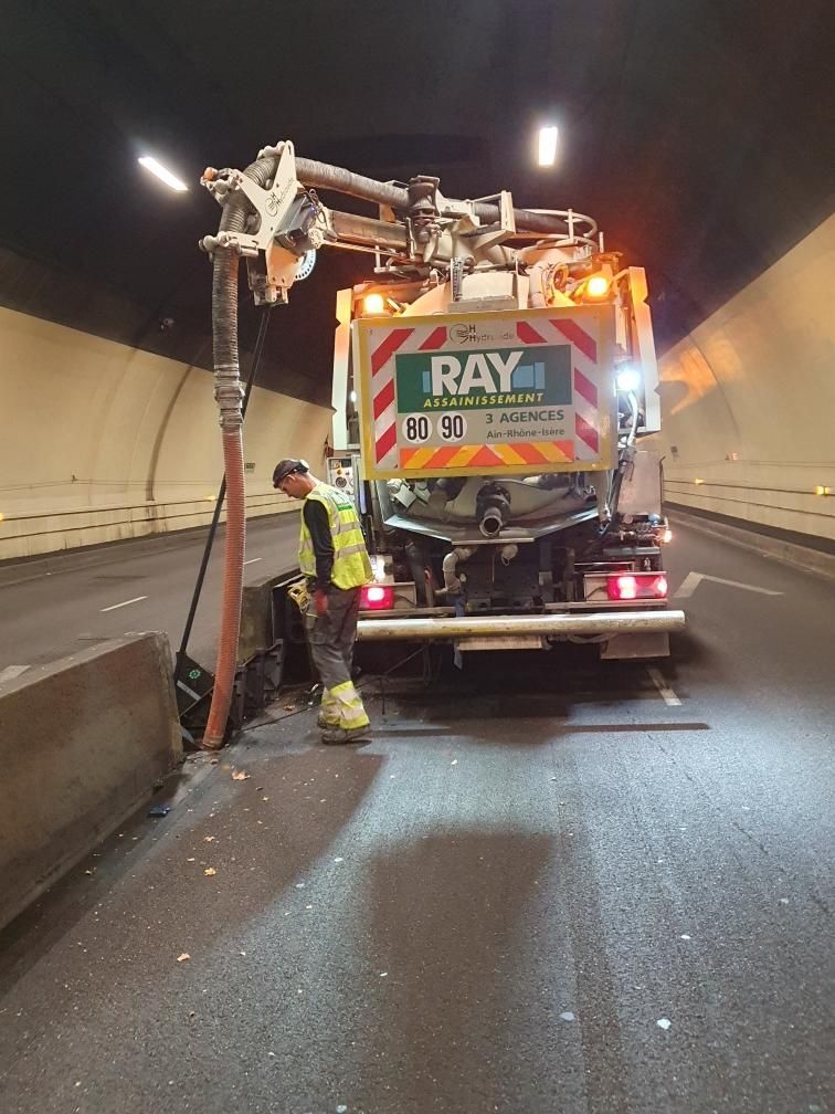 Un ouvrier manœuvre un camion aspirateur dans un tunnel. Le camion porte le logo de Ray Assainissement.