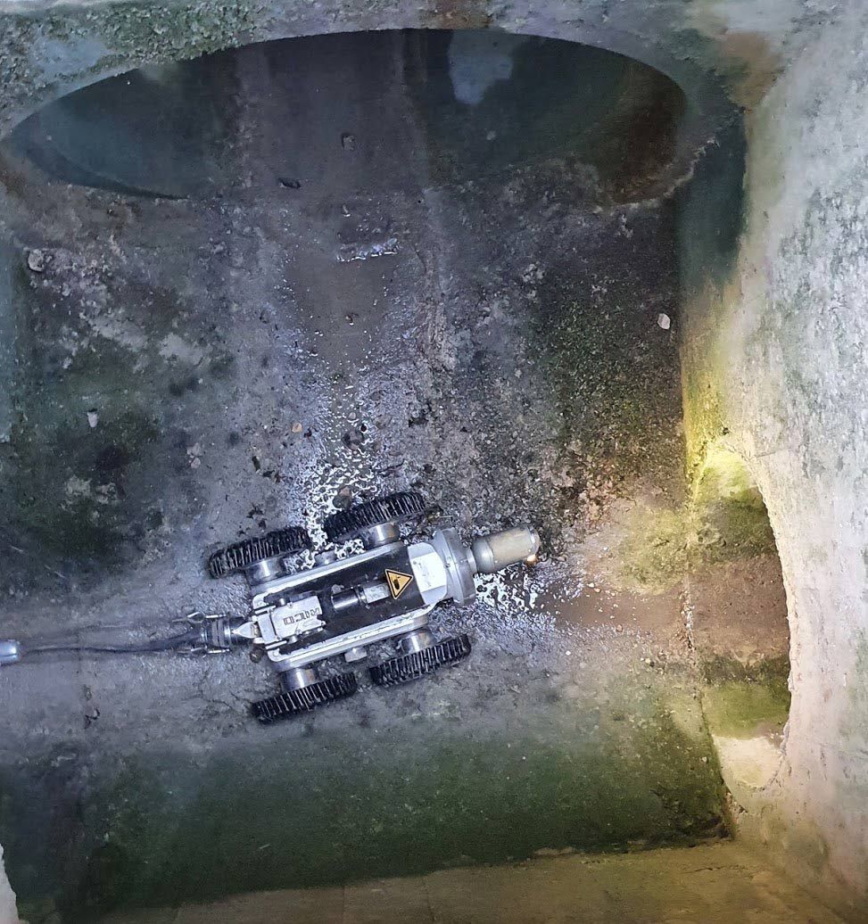 Un petit robot d'inspection dans une structure souterraine en béton ; le robot est positionné sur le sol.