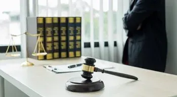 El mazo de un juez está sobre una mesa al lado de una balanza de justicia.