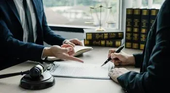 Dos abogados están sentados en una mesa hablando entre sí.