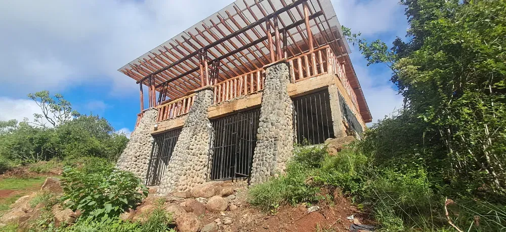 A large stone building is sitting on top of a hill surrounded by trees.