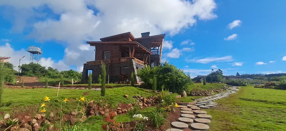 A large house is sitting on top of a lush green hillside.