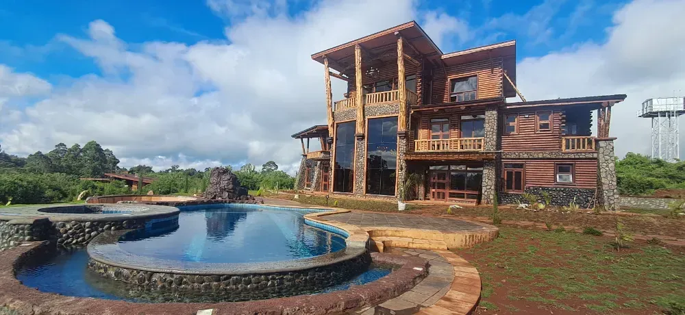 A large wooden house with a swimming pool in front of it.
