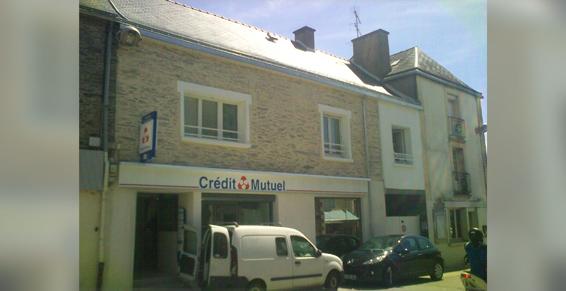 Une banque Crédit Mutuel avec une camionnette blanche garée à l'extérieur par une journée ensoleillée.