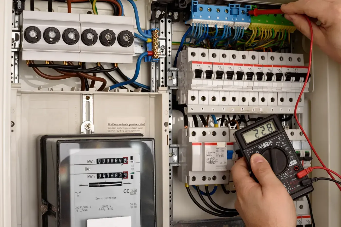 Eine Person testet mit einem Multimeter einen Sicherungskasten.